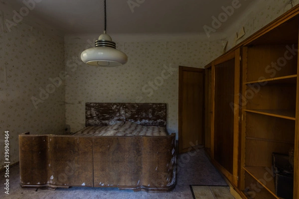 Fototapeta bedroom with a lamp and a moldy wooden bed in a house
