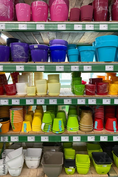 Fototapeta Variety of colorful flower pots are sold at the store. Rows of different pots for indoor plants on shelves in a mall. Vertical view.