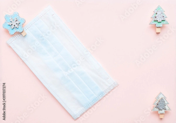 Obraz medical protective face mask and figures of Christmas trees and snowflakes wooden on a pink background. Decor Christmas and New Year 2021. Holidays self-isolation and coronavirus pandemic concept