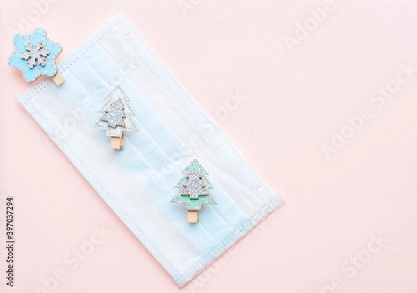 Obraz medical protective face mask and figures of Christmas trees and snowflakes wooden on a pink background. Decor Christmas and New Year 2021. Holidays self-isolation and coronavirus pandemic concept