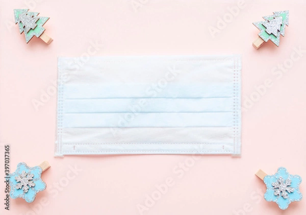 Obraz medical protective face mask and figures of Christmas trees and snowflakes wooden on a pink background. Decor Christmas and New Year 2021. Holidays self-isolation and coronavirus pandemic concept
