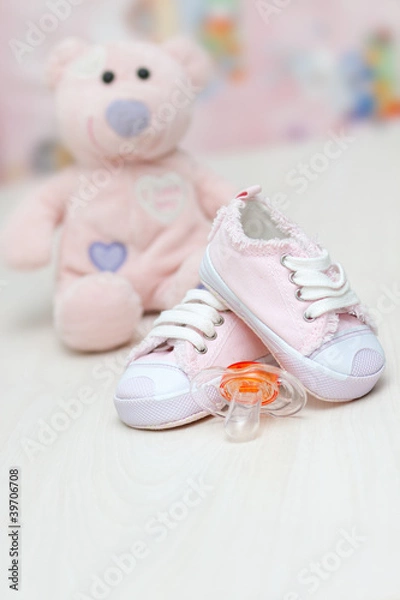 Obraz baby shoes and teddy bear toy on a wooden floor