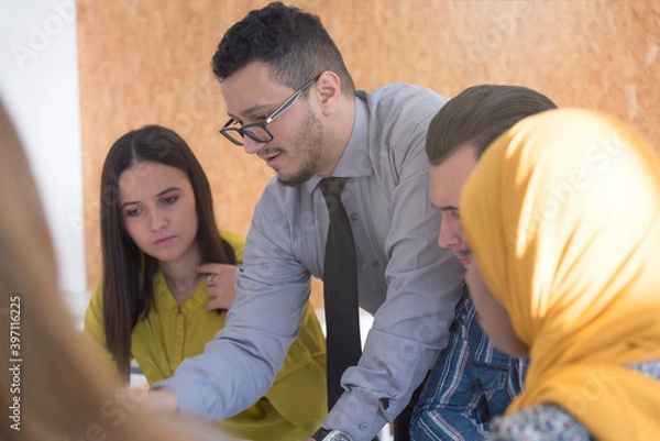 Fototapeta Male professor of architecture explain lesson to multiethnic students and interact with them in the modern classroom.Helping a students during class.
