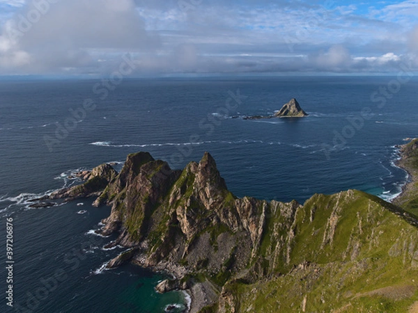 Obraz Aerial panoramic view of the northwestern coast of Andøya island, Vesterålen, Norway with rugged mountains, cliffs and famous bird rock Bleiksøya on sunny summer day with clouds.