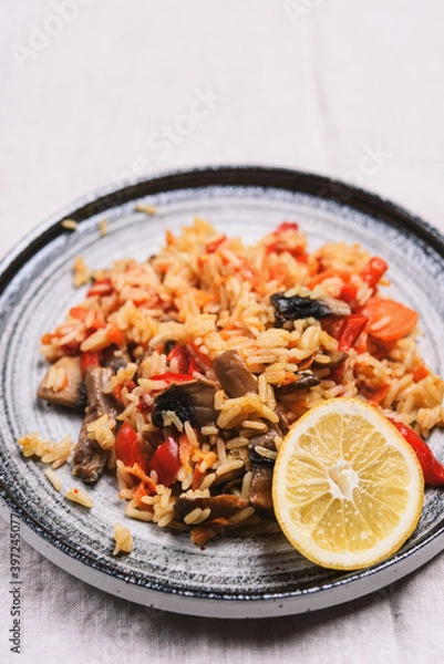 Fototapeta Arroz con verduras y azafran, spanish dish. Vegetarian risotto with  vegetables, champignons and saffron on beige linen tablecloth. Selective focus