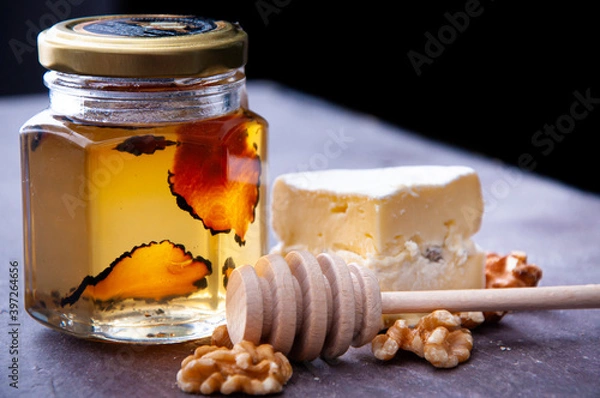 Obraz Jar of raw honey infused with truffle. A delicious accompaniment to breakfast or snack served with brie cheese and garnished with walnuts.