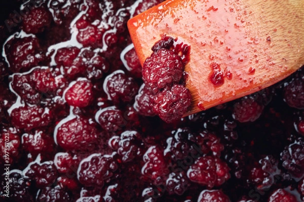 Fototapeta Close up of stirring blackberries and sugar making homemade blackberry jam with wooden utensil.