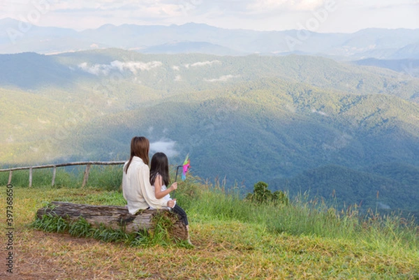 Fototapeta Mother and daughter sit and watch the beautiful mountain view Look at the vast nature