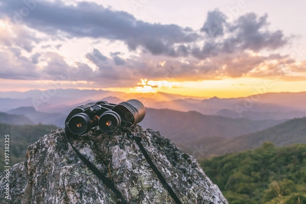 Fototapeta binoculars on top of rock mountain at sunset