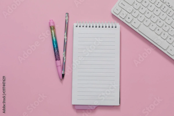 Fototapeta Flat lay of weekly planner, clear notepad, keyboard, glitter holographic pens are on pink background. Concept of online, homeschooling, back to school, home office. Blank, copy space.