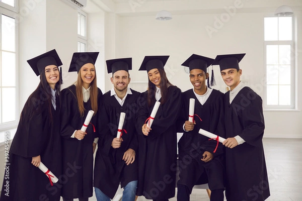 Fototapeta Group of young happy university graduates multiethnic friends with diplomas in hands