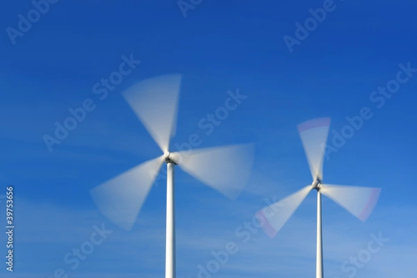 Fototapeta Two wind turbines in movement against blue sky