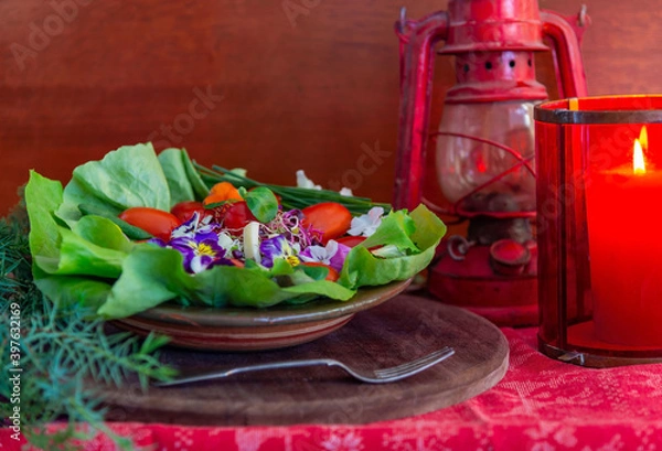 Obraz new Year's still life with salad of tomato, cheese, green onions and tricolor violet flowers, and a candle