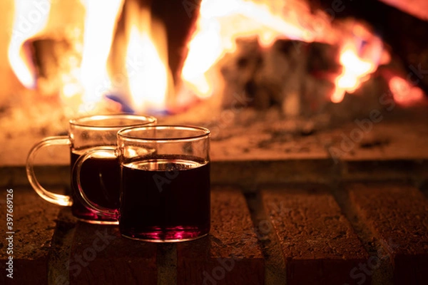 Obraz Two cups of wine by the fire, mulled wine cozy time