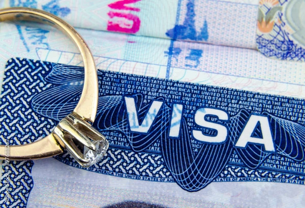Obraz Engagement ring on top of blurred US entry visa sticker in a passport. Conceptual photo for fiance visa and immigration in general. Selective focus.