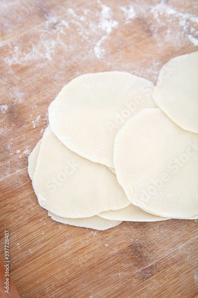 Fototapeta Close-up looking down on white flour dumpling wrappers on cutting board