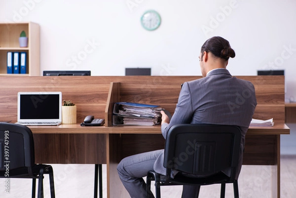 Fototapeta Young male employee working in the office