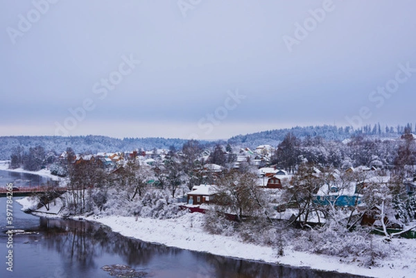 Fototapeta  A snow-covered village on the Bank of a river .