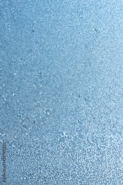 Fototapeta Vertical image of a winter background on a transparent glass window with a frozen texture. Abstract texture background, vertical photo, copy space for your design or text