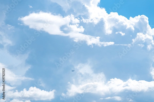 Fototapeta Airplane flying in the blue sky among clouds and sunlight