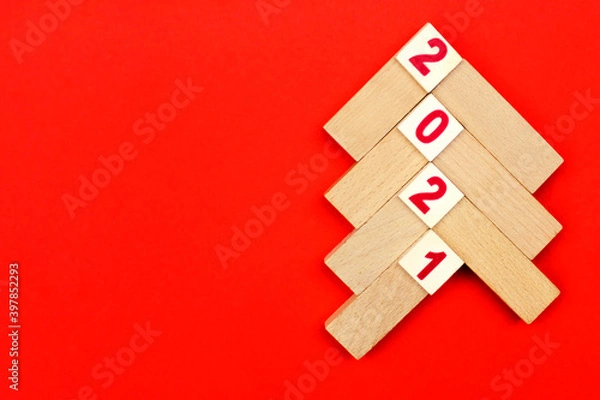 Fototapeta Christmas tree made of light wooden bars on a red background with the numbers 2021