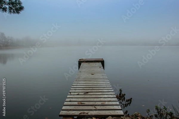 Fototapeta Mysterious morning by lake. Foggy autumn mystery atmosphere. Wooden pier on the pond.Magic mood. Misty fall day. Speechless place. Relaxing meditation without people.Silence scene.Serenity background.