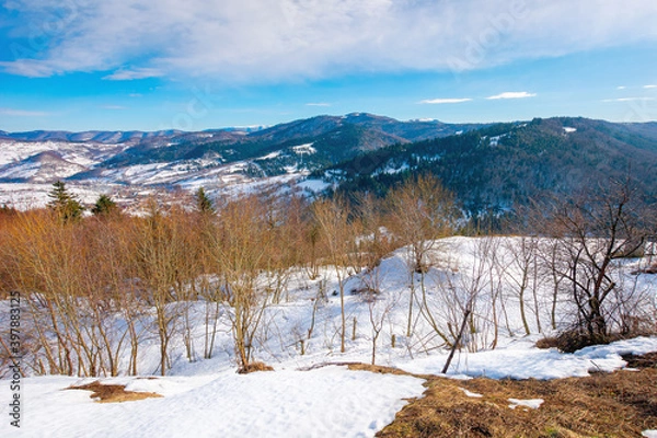 Obraz mountainous countryside on a sunny day. late winter scenery or beginning of spring. melting snow and leafless trees on the hills. village in the distant valley. transcarpathia, ukraine