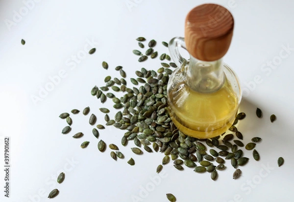 Fototapeta Raw papitas - no shell pumpkin seeds and pumpkin seed oil bottle on white.