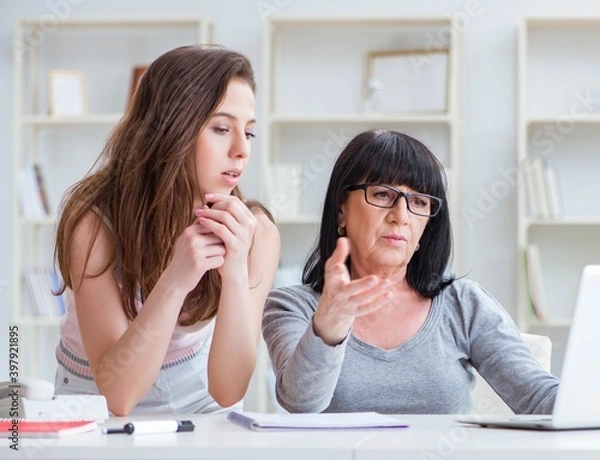 Fototapeta Daughter explaining to mom how to use computer