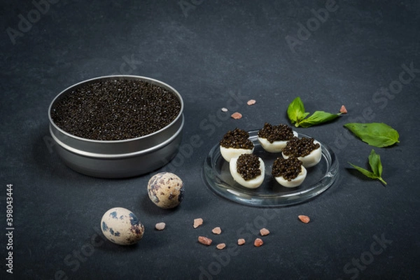 Obraz Black caviar of sturgeon in the quail eggs on a dark background. New Year's feast.