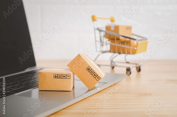 Fototapeta Brown paper boxs with laptop on wood table in office background.Easy shopping with finger tips for consumers.Online shopping and delivery service concept.