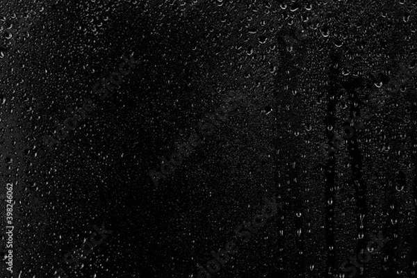 Fototapeta Drops of water flow down the surface of the clear glass on a black background. Texture for creativity.
