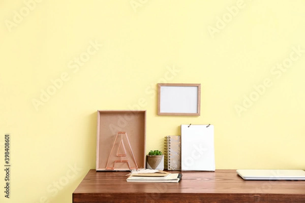 Fototapeta Stylish workplace with blank photo frame near color wall