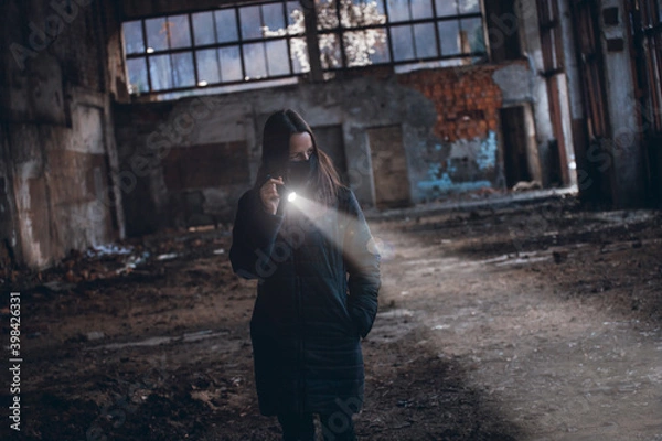 Fototapeta Lonely Girl with a Flashlight Walks in an Abandoned Room