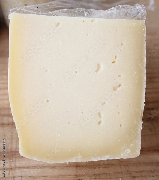 Fototapeta Farmer's cheese crust of cheese with grains inside. the texture as it Matures is handmade. pieces of cheese on a cutting Board in different colors of Derby, caciotta, cheddar