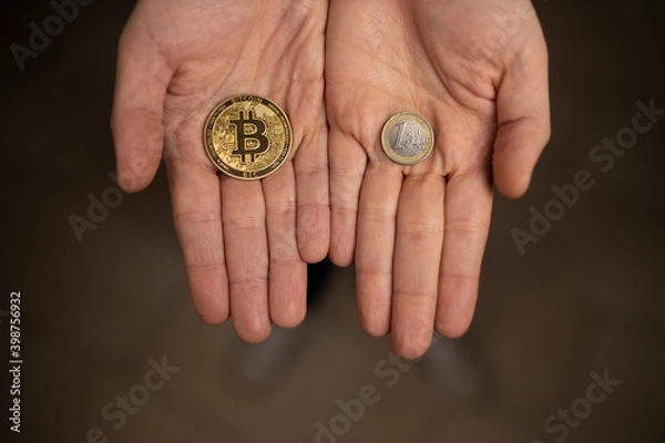 Fototapeta Caucasian hands shows one Bitcoin coin and one Euro Coin. New finance concept. Comparison between currencies, fiat and crypto. Two hands