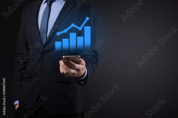 Fototapeta Businessman holding tablet and showing a growing virtual hologram of statistics, graph and chart with arrow up on dark background. Stock market. Business growth, planing and strategy concept.