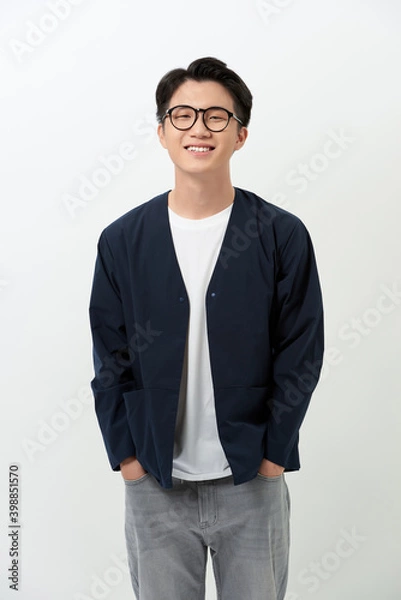 Fototapeta Cheerful young Asian handsome man putting his hands in his pockets over white background.