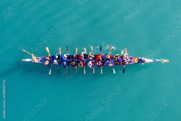Obraz Dragon Boat team rowing to the pace of an onboard Drummer, Aerial view.
