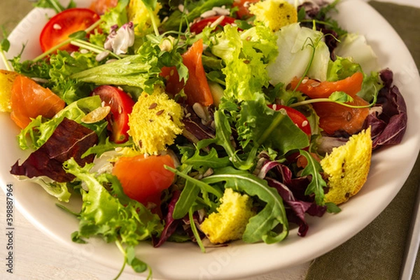 Fototapeta Light breakfast or dinner, mix salad with salmon and different seeds, plate with salad and cornbread close up