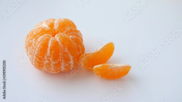 Fototapeta Peeled whole tangerine and two tangerine slices isolated on white background. Vitamins. Place for your text. Selective focus.