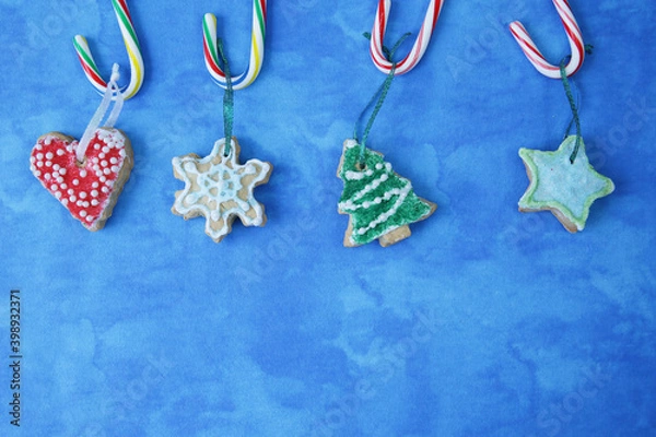 Fototapeta flat lay composition Christmas cookies in the form of a Christmas tree, snowflakes, stars and hearts hanging on canes or caramel with copy space for text. Frame, background, pattern, banner.