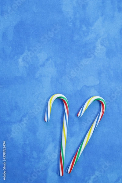 Fototapeta flat lay sweet cane or caramel candies blue and white christmas background or composition. card, pattern, frame, background. copy space for text. vertical photo
