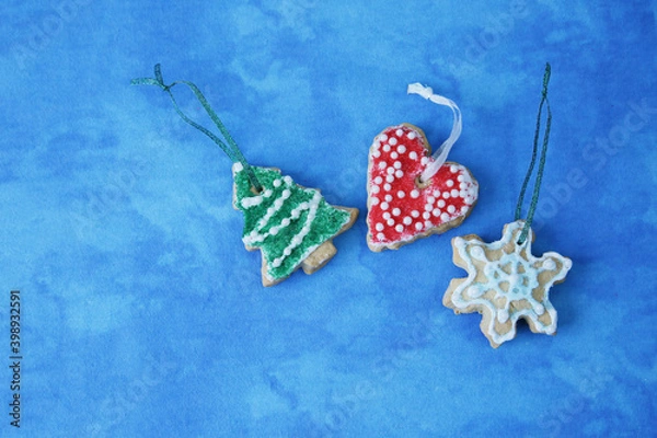 Fototapeta Flat lay Christmas cookies in the form of a Christmas tree or spruce, snowflakes and a heart with copy space for text. Frame,  blue background, pattern, banner, card. Christmas decoration, ornament.