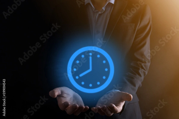Fototapeta Businessman hand holds the icon of hours clock with arrow. Rapid execution of the work.Business time management and business time is money concepts
