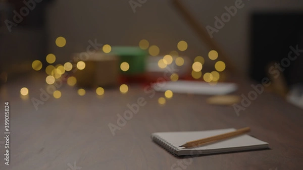 Fototapeta Notepad with pencil on walnut wood table with christmas lights on background