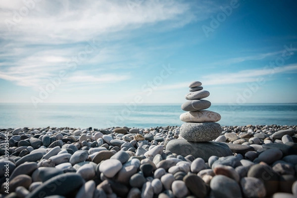 Fototapeta A column of gray stones on the seashore against the background of a blue clear sky