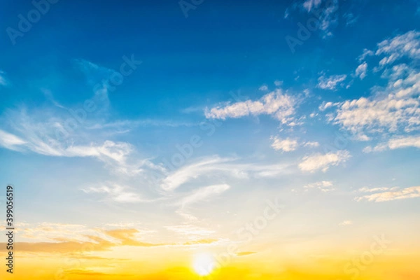 Obraz Sky at sunset blue and orange light of the sun through the clouds in the sky