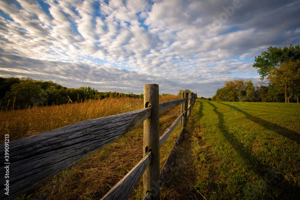 Fototapeta fence in the field with shadows at sunset