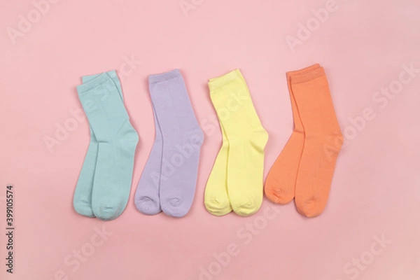 Fototapeta Colored children's socks without a pattern, pink, lilac, yellow, orange on a pink background with a place for text, copy space, flatly, minimal style. Concept for children's clothing, housekeeping